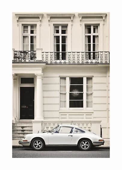 White classic sports car parked in front of a cream townhouse with balcony and tall windows