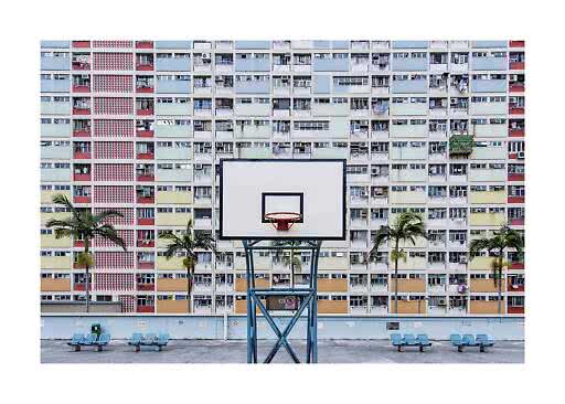 Basketball hoop in front of a colorful apartment block with palm trees and benches
