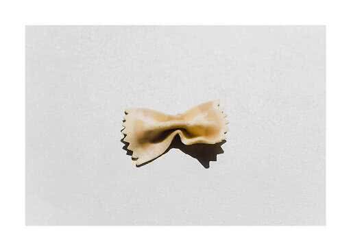 En enkelt farfalle-pasta på hvid baggrund med tydelig skygge