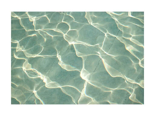 Sonnenlicht spiegelt sich in hellen Mustern auf türkisfarbenem Poolwasser