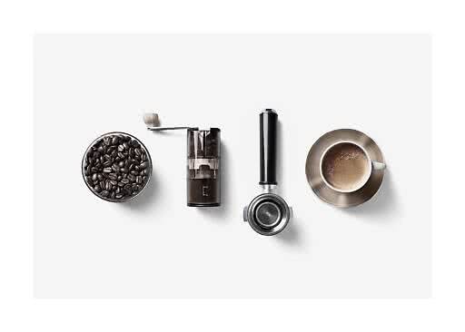 Skål med kaffebønner, håndkværn, portafilter og kop kaffe set ovenfra på hvid baggrund