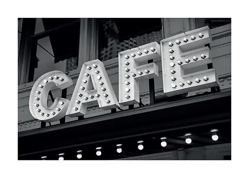 Foto in bianco e nero di un'insegna café illuminata con lampadine su edificio