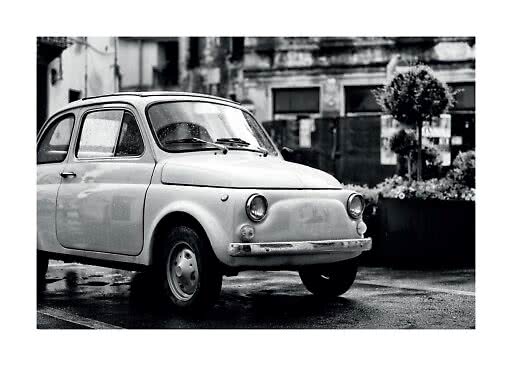 Black-and-white photo of a small vintage car parked on a wet street
