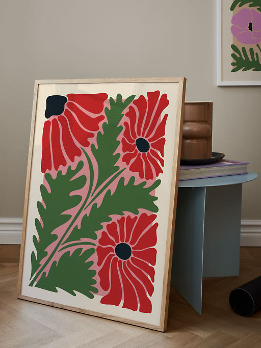 Framed floral print with red flowers and green leaves, leaning against a small side table