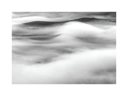 Paesaggio in bianco e nero con cime montuose avvolte da nuvole e nebbia