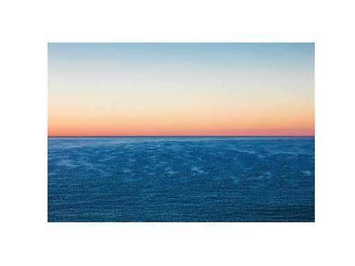 Mar en calma bajo un cielo en tonos pastel al atardecer