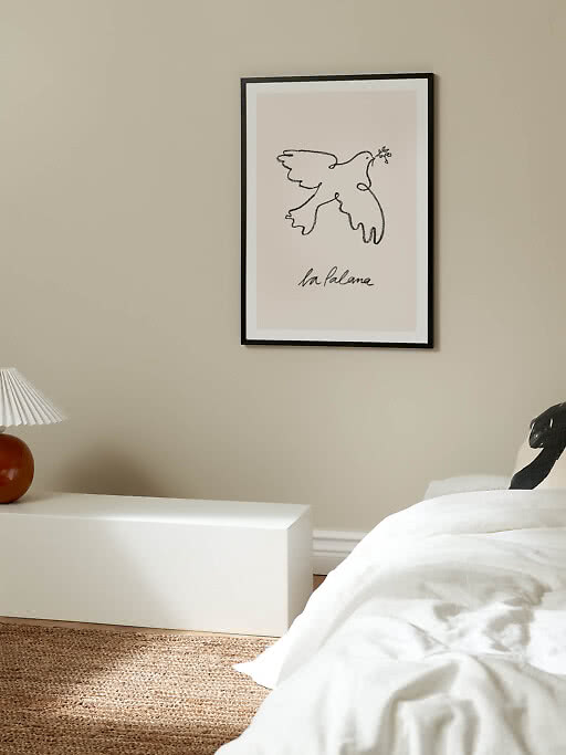 Affiche encadrée avec dessin au trait d’une colombe tenant un rameau d’olivier sur mur beige