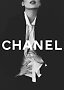 Black-and-white fashion image of model in black blazer and white shirt with Chanel logo across center