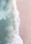 Aerial view of waves washing onto a pink sand beach