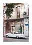White vintage car parked in front of a weathered building with columns and balcony