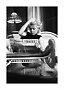 Foto en blanco y negro de mujer en silla de mimbre leyendo una revista bajo una lámpara