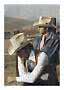 Zwei Männer mit Cowboyhüten und Westernkleidung an einem Zaun in trockener Berglandschaft