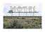 Large vintage motel sign with arrow in open scrubland under a cloudy sky
