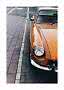 Close-up of an orange vintage car parked by the curb on a city street