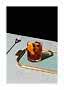 Low glass with dark drink, ice cubes and orange slice on a gold-toned tray.