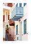 Narrow alley with white houses, blue balconies and windows, red steps, and potted plants