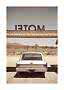 Rear view of a silver vintage car under a motel sign in a desert landscape