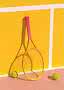 Farverigt tennisbat med pink håndtag og to tennisbolde på gul banevæg