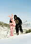 Person in pink bunny costume and person in black gorilla suit skiing in snowy mountains