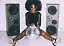 Woman with afro and sunglasses sits between two speakers with a disco ball in front