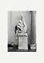 Photo en noir et blanc d'une sculpture de main en pierre sur socle, index levé