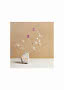 Minimalistisches Stillleben mit getrockneten Gräsern und violetten Blumen in rauer steinartiger Vase.