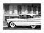 Foto in bianco e nero di un'auto d'epoca bianca parcheggiata davanti a un motel con tende alle finestre.