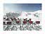 Sedie a sdraio con coperte rosse sulla neve davanti a piste da sci e montagne innevate