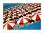 Crowded beach with red and white umbrellas and loungers by the blue sea