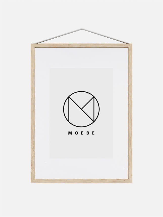 Heller Holzrahmen mit weißem Passepartout und MOEBE-Logo, an einer Schnur hängend